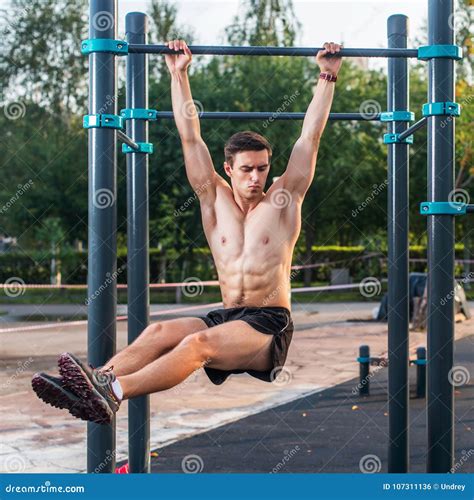 Athlete Hanging on Fitness Station Performing Legs Raises. Core Cross