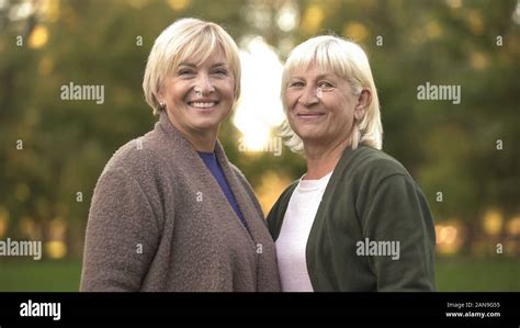 cheerful mature females hugging smiling  camera enjoying pastime
