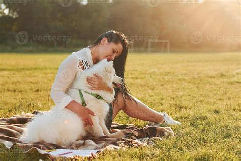Woman with her dog is having fun on the field at sunny daytime
