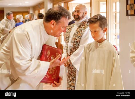 In the back row of a Catholic church in Laguna Niguel, CA, a deacon instructs a serious young ...