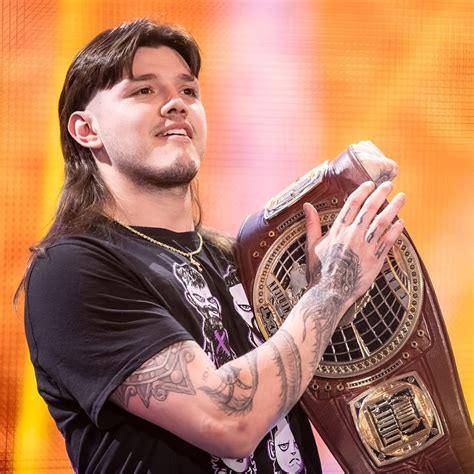 a man with long hair and tattoos holding a wrestling belt in front of ...