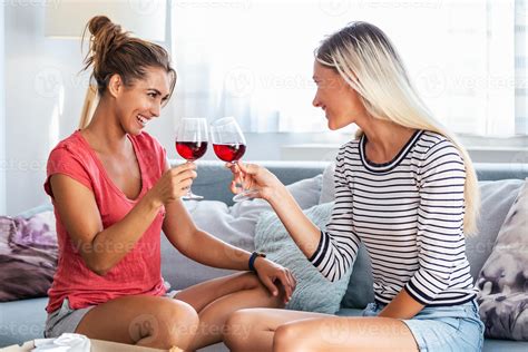 Two attractive girls, cheerful best friends having fun and drinking red