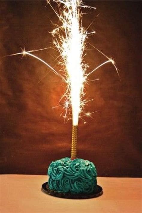 a green cake with sparklers on top is sitting on a table in front of a ...