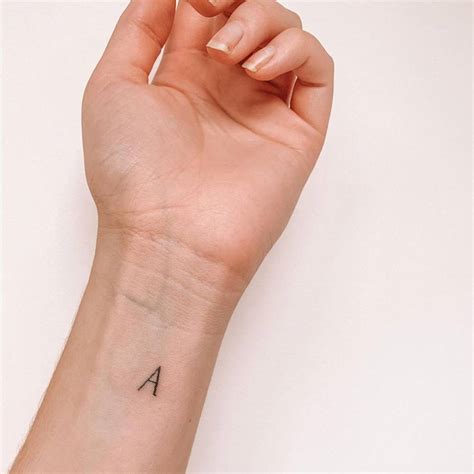 Minimalist letter "A" tattoo on the wrist.