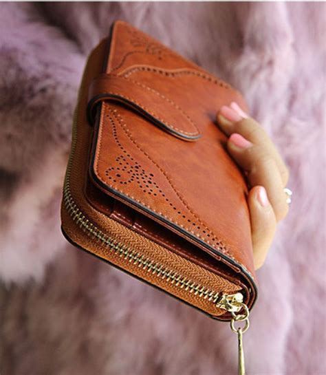 a woman is holding a brown wallet in her hand