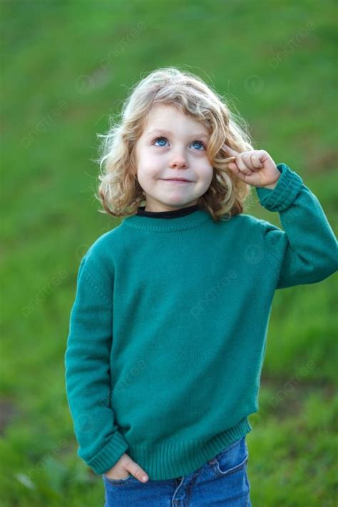 Small Blond Child With Green Jersey Imagining Something In The Field