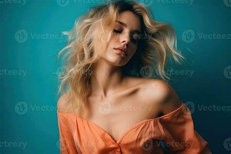 Portrait of young pretty blonde woman in light orange dress in studio ...