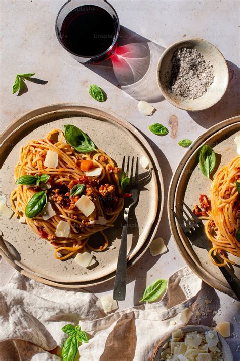 Two plates of spaghetti with basil and parmesan cheese photo – Pasta ...