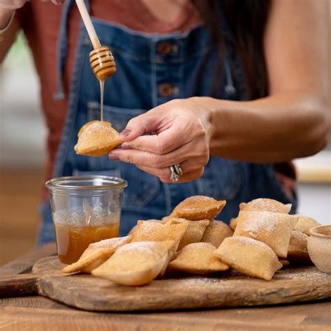 a woman is dipping honey into some bread