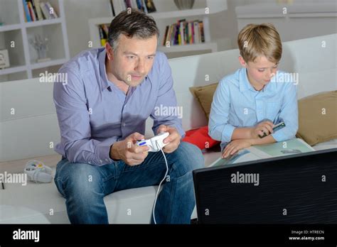 adult playing computer game child photographing book stock photo alamy