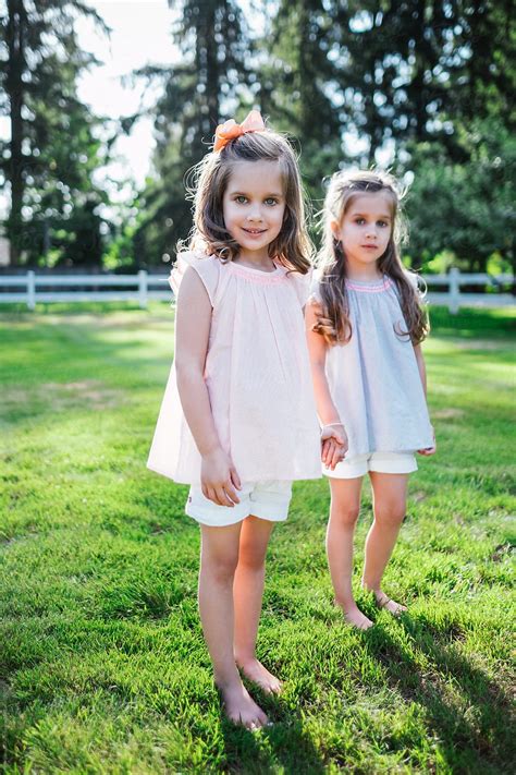 "Young Twin Sisters In The Front Yard Of Their Home" by Stocksy