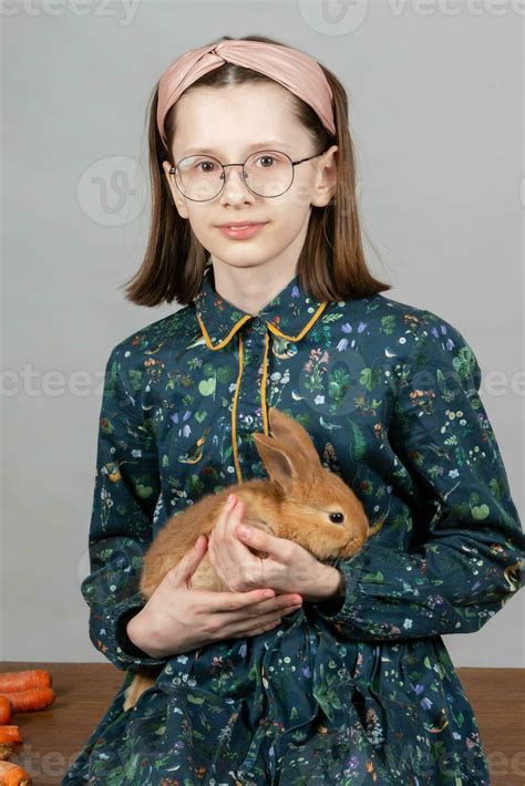 Portrait of a girl in glasses with a red rabbit. Child with a rabbit