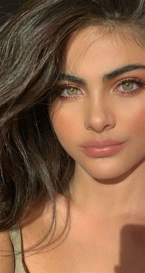 a close up of a woman with long dark hair and green eyes wearing a tan ...