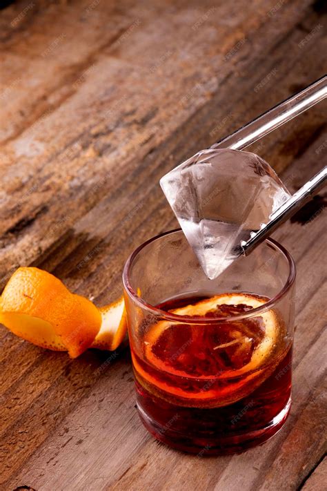 Premium Photo | Putting diamond ice into red negroni drink with campari ...