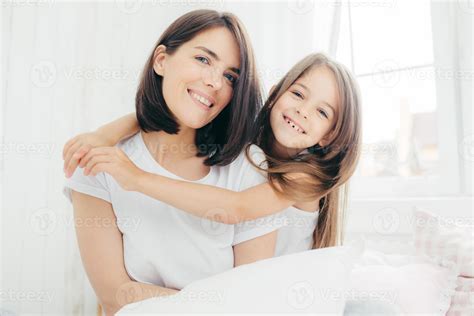 Portrait of happy Caucasian mother with charming smile and her small