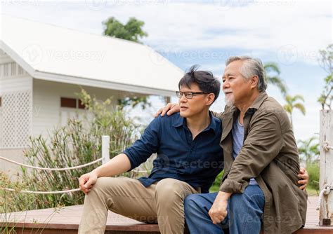 Senior asian father and middle aged son sitting relax together outdoors