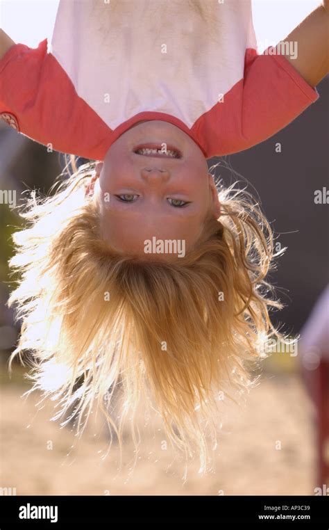 Young girl hanging upside down in the park on an autumn day Stock Photo
