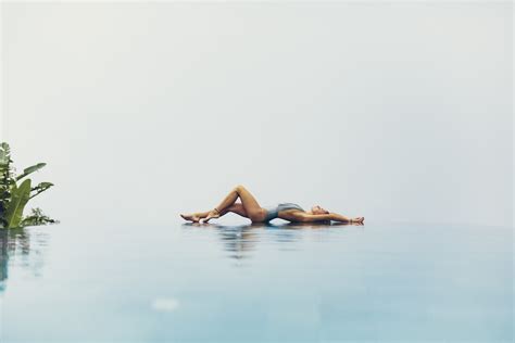 Flexible woman lying on poolside against cloudless sky · Free Stock Photo