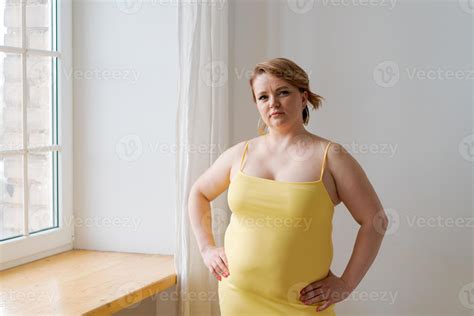 Portrait cheerful attractive young plump plus size woman in yellow