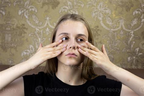 Young girl massages her face with hands for skin care, warming up the