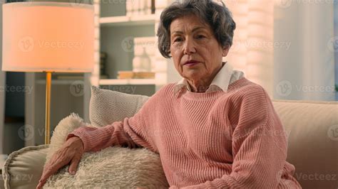 Caucasian old woman tying to stand up from home couch feel sudden pain