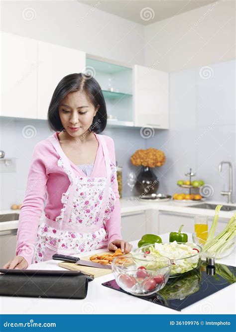 Asian Housewife Wearing An Apron And Standing To Washing Lettuce And