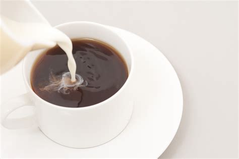 Pouring milk into a cup of coffee - Free Stock Image