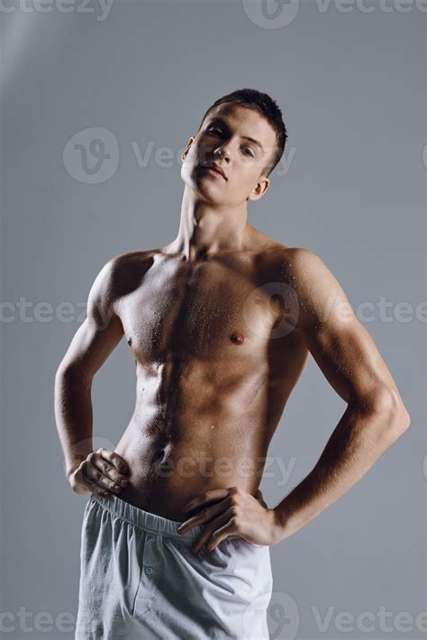 half-naked athlete in white shorts holding hands on the belt on a gray