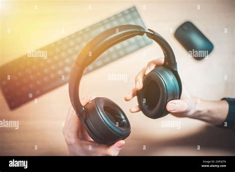 male hands  holding black wireless headphones workspace stock photo