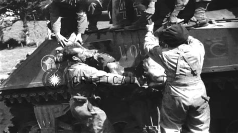 French tank crew removing body of dead soldier from tank and laying him ...