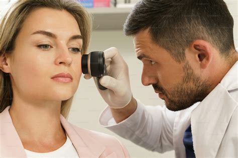 Doctor and client woman in dermatology clinic. Dermatologist is using