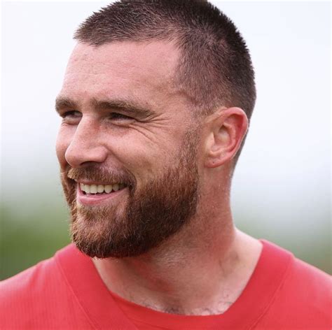 a man with a goatee and beard smiling at the camera while wearing a red ...