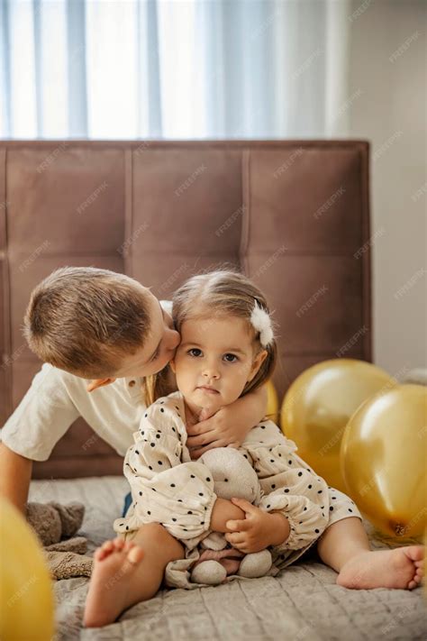 Irmão Comendo A Irmãzinha - Um irmão está beijando sua irmãzinha enquanto está sentado em uma cama ...