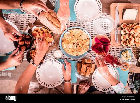 Top view of colorful table full of mixed culture food and hands and people eating and having fun ...