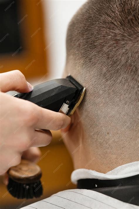 Premium Photo | Barber uses clipper on mans hair near forehead ear chin