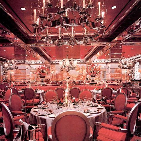 a fancy dining room with chandeliers and round tables set for four ...