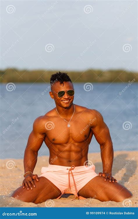 Muscular Young Athletic Man on the Beach with a Naked Torso in