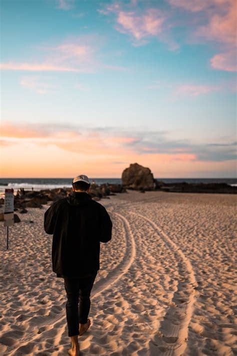 Back View of a Man Walking on a Beach at Sunset · Free Stock Photo