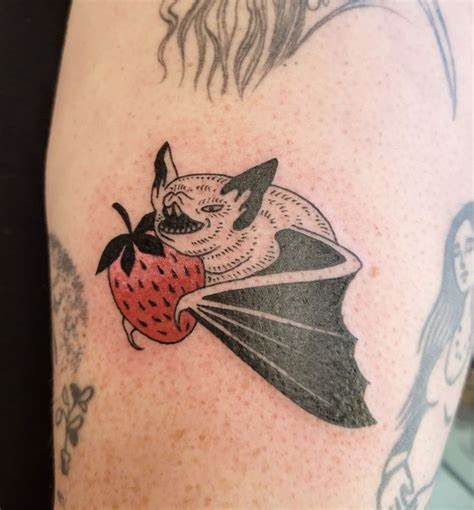 a person with a bat and strawberry tattoo on their arm