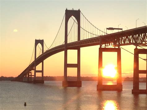 the sun is setting behind a large bridge