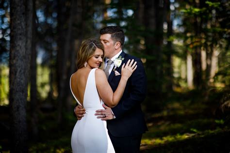 The bride poses while the groom gives her a kiss in a backless sexy
