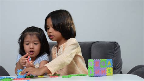 Cute Asian sister same pregnant siblings playing with colorful toy ABC