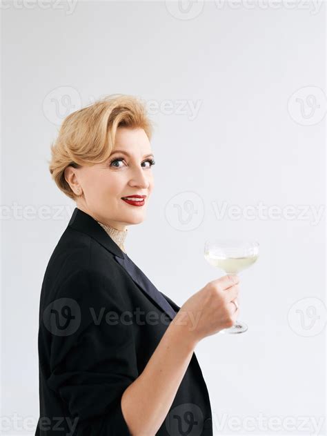 mature stylish elegant woman in tuxedo with glass of sparkling wine