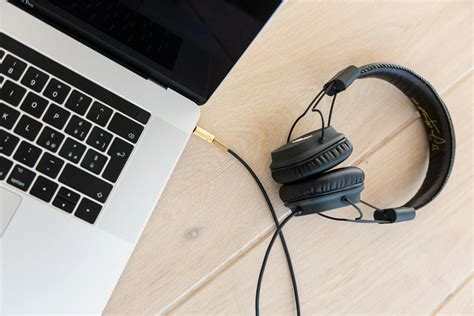 black corded headphones plugged  macbook pro  brown wooden surface