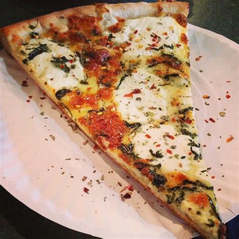 a slice of pizza sitting on top of a white paper plate covered in ...