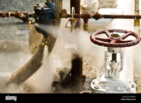 A red valve and a check valve releasing steam Stock Photo - Alamy