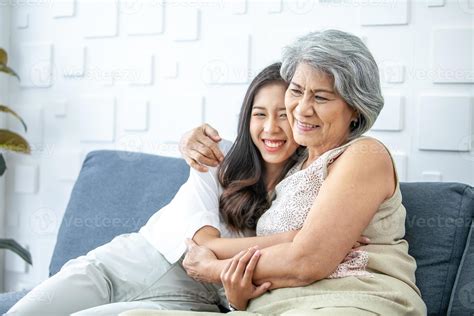 Asian grandma and granddaughter hugged with happy mood on the sofa in