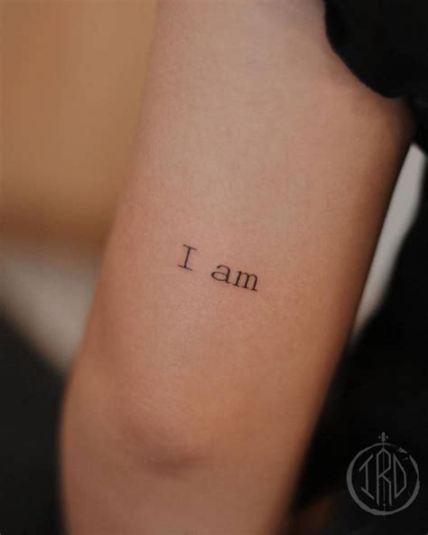 "I am" lettering tattoo located on the tricep.