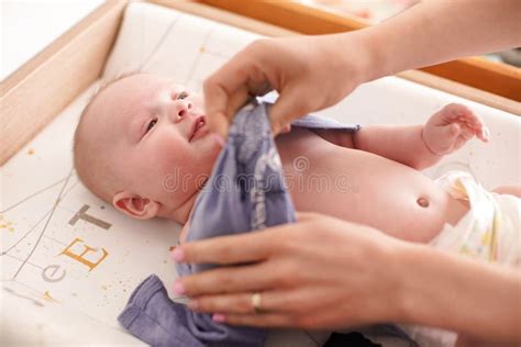 Mother Changing Infant Baby Clothes on the Table, Detail To Her Smiling ...