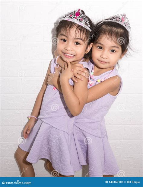 Female Asian Identical Twins Sitting on Chair with White Background